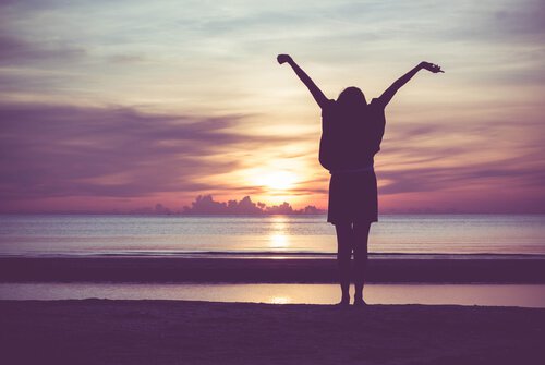 Femme-etirant-ses-bras-devant-coucher-de-soleil