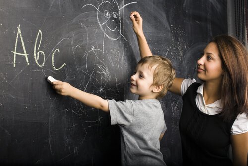 Maestra-con-niño-en-la-pizarra-dibujando