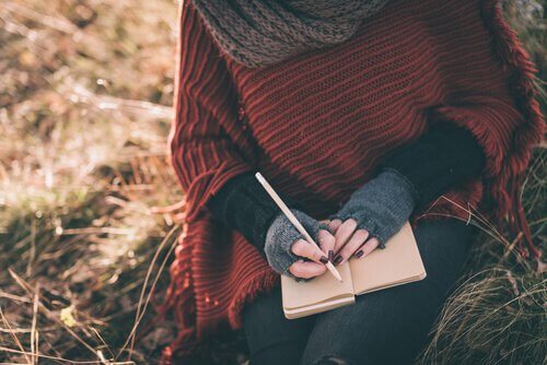 Mains-de-femme-ecrivant-sur-un-carnet-dans-un-champ