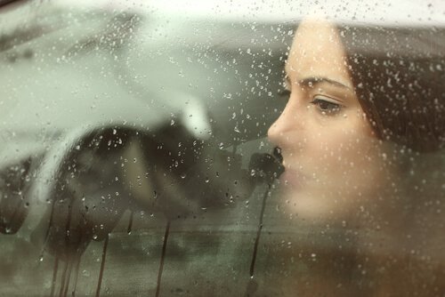 Mujer-triste-llorando-tras-un-cristal-con-gotas-de-lluvia