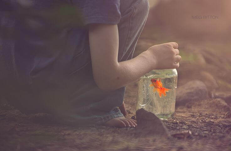 enfant avec un bocal contenant un poisson rouge
