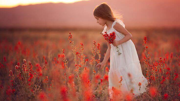 fille dans un champ de fleurs rouges