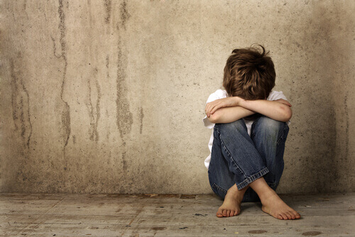 Enfant-triste-assis-sur-le-sol-les-bras-croises