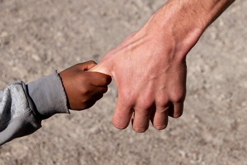 Mano-de-un-niño-sirio-cogiendo-la-de-un-adulto-de-raza-blanca