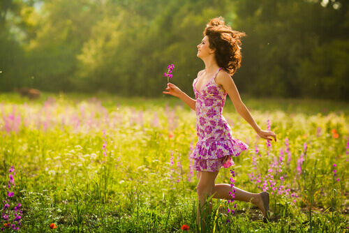 Mujer-caminando-entre-flores-sonriendo-y-feliz