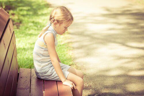 Enfant-blonde-assise-sur-un-banc-triste