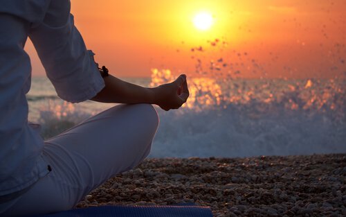 mujer-haciendo-meditacion-en-la-arena-de-la-playa