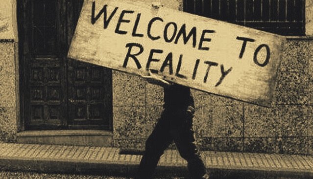 personne portant un panneau "welcome to reality"