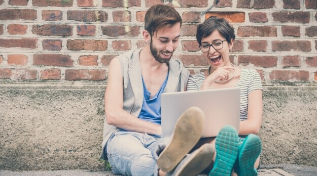 couple riant devant un ordinateur