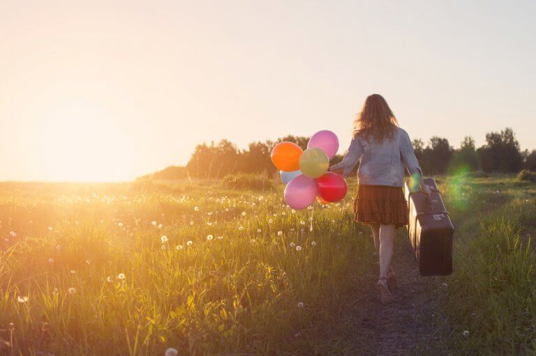 femme sur un chemin avec des ballons et une valise