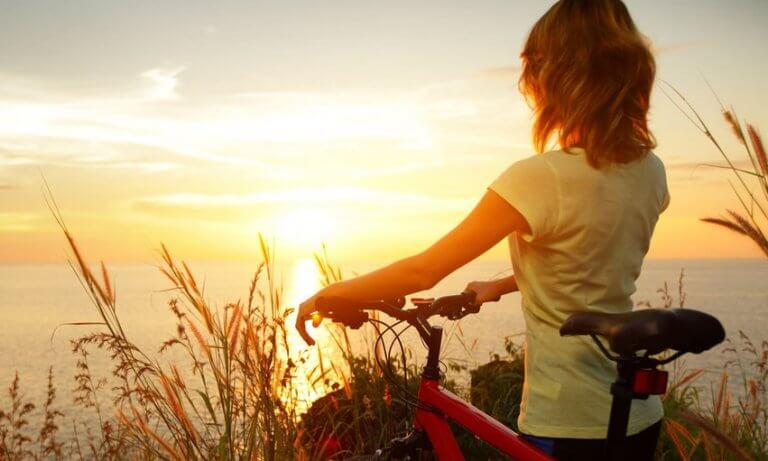 femme à vélo regardant le coucher de soleil