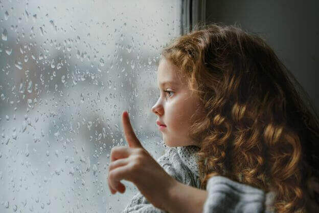 fille qui regarde par la fenetre pendant qu'il pleut