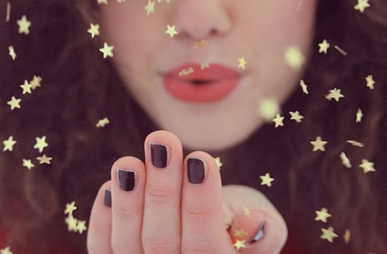 fille soufflant sur des paillettes en forme d'étoiles