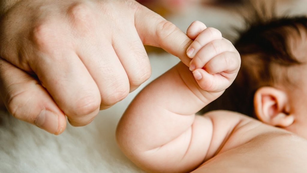 bébé serrant le doigt de son père