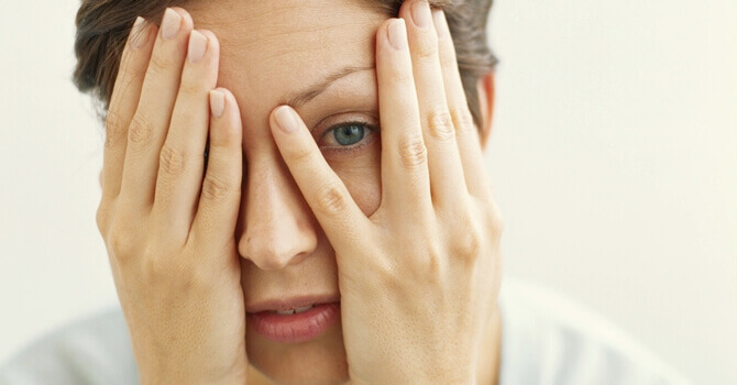 femme qui se cache le visage avec les deux mains