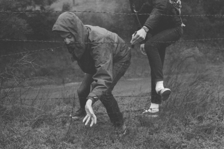 personnes passant sous des fils barbelés