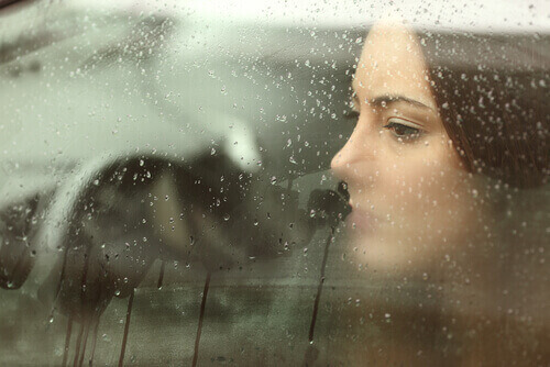 femme regardant la pluie par la fenêtre