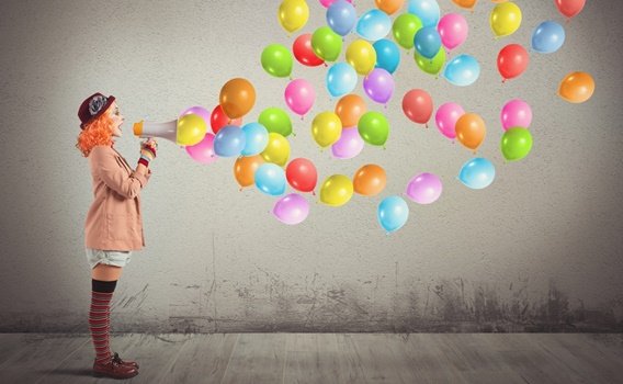 femme clown avec mégaphone d'où sortent des ballons
