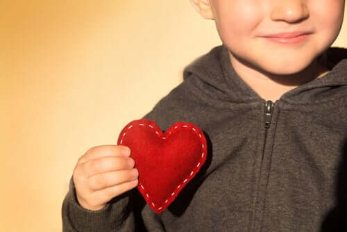 Un petit garçon qui tient un coeur avec sa main