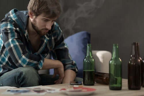 Un jeune homme face à une table contenant des bouteilles d'alcool