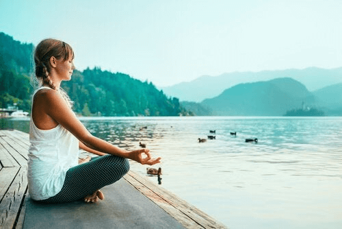 Une femme qui s'adonne au mindfulness au bord d'un lac