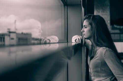 Une femme regarde par la fenêtre et pense à sa relation à distance