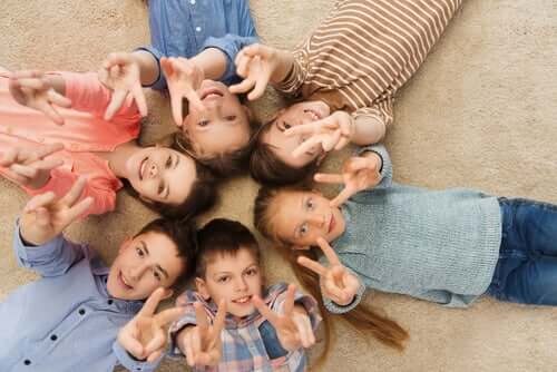Des enfants allongés sur le dos faisant le signe de la paix