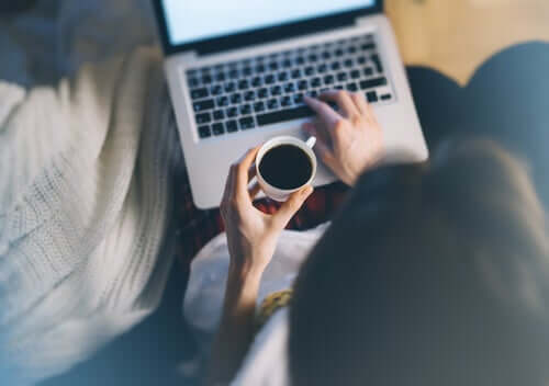 Une femme avec son café sur son ordinateur