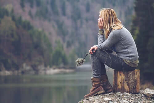 Une femme pensant au voyage face à un lac