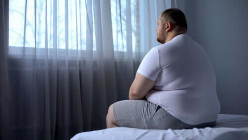 Un homme assis sur le lit regardant par la fenêtre