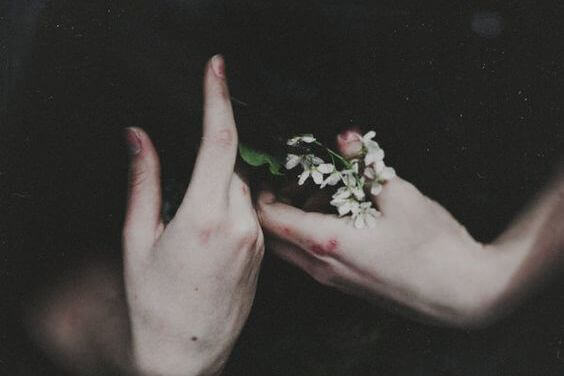Des mains ayant subi l'automutilation qui tiennent des fleurs