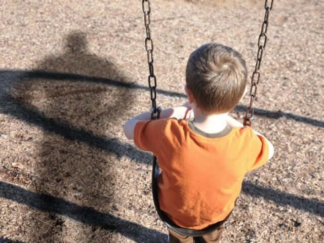 Un enfant sur une balançoire vu de dos