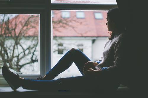 Une femme à la fenêtre se confiant pour se protéger et protéger les autres de la pandémie