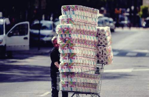 Un homme avec un chariot rempli de papier toilette