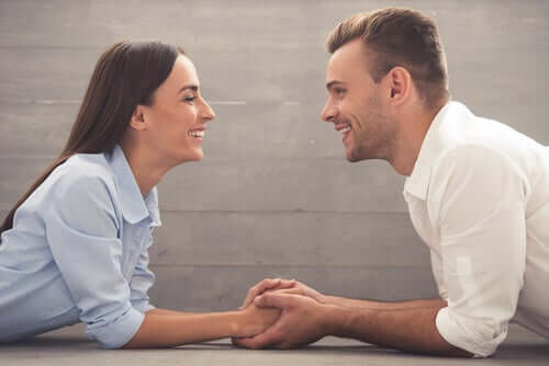 Un couple se tenant les mains en se souriant et en maintenant le contact visuel