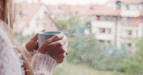 Une femme à sa fenêtre avec un café tentant d'affronter l'isolement