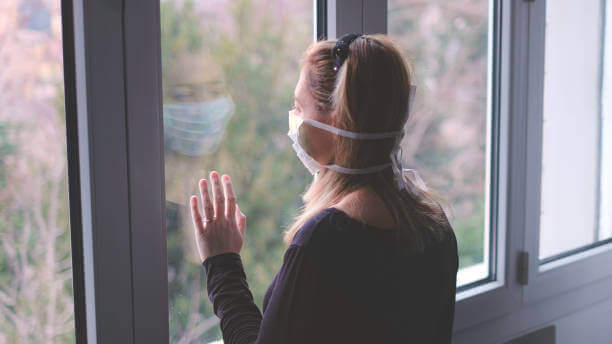 Une femme à la fenêtre avec un masque