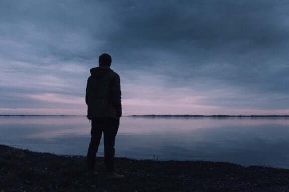 Un homme est debout face à la mer se posant des questions du fait de la dépression existentielle