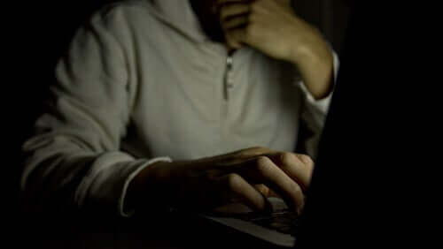 Un homme regardant de la pornographie sur son ordinateur dans le noir