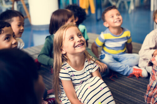Des enfants souriants en classe face à l'arbre des valeurs
