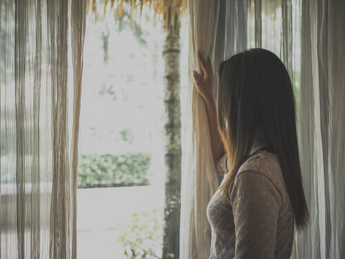 Une femme regardant par la fenêtre durant le confinement