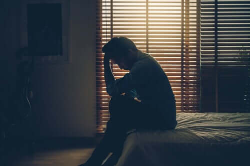 Un homme pleurant sur son lit car en deuil