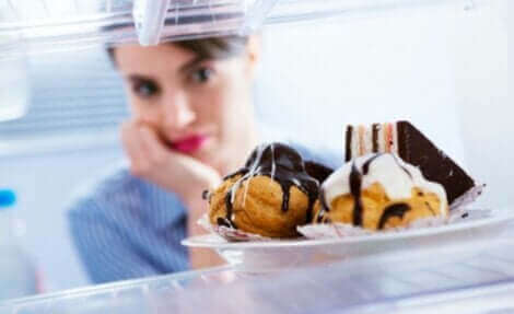 Une femme qui regarde une assiette remplie de desserts.