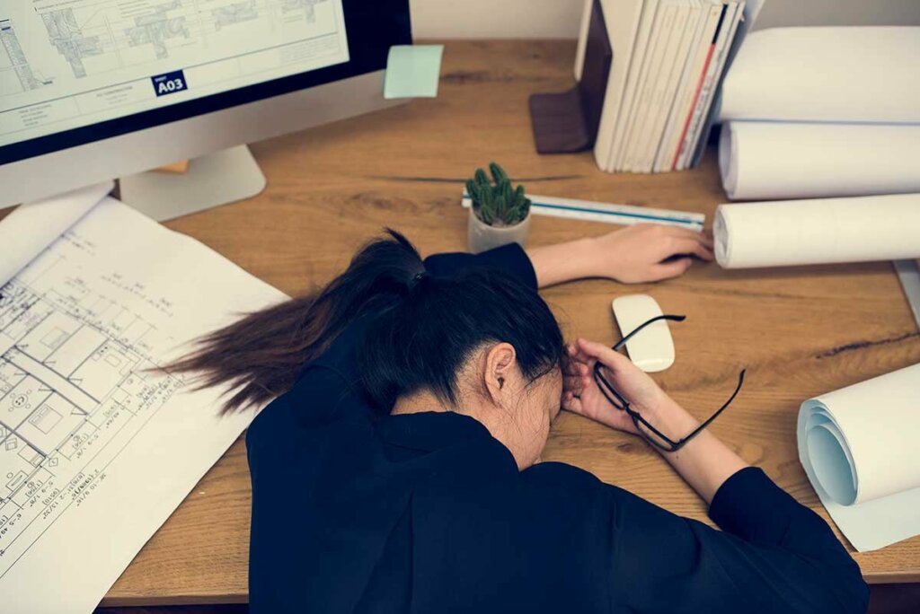 Une femme épuisée affalée sur son bureau.