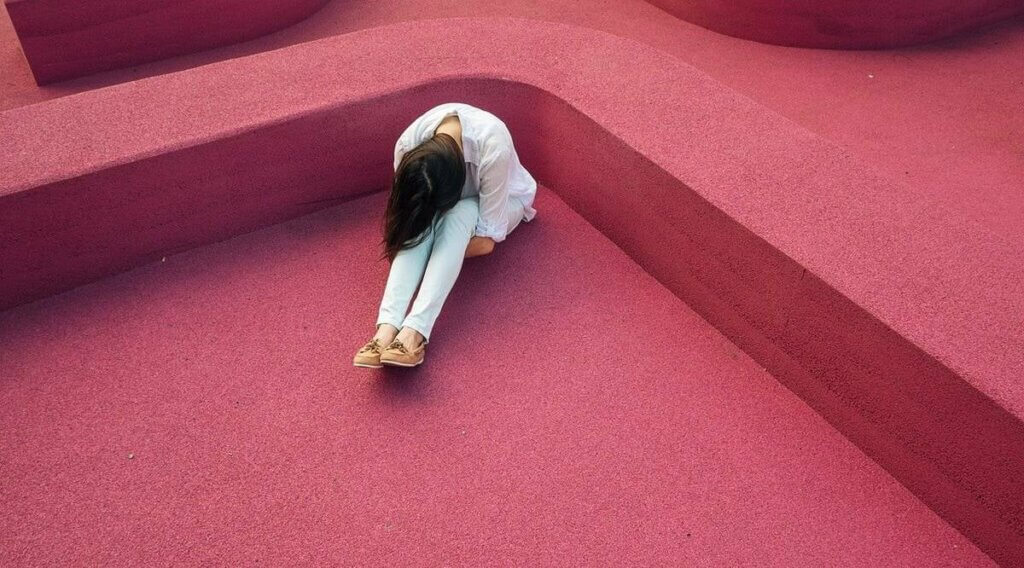 Une femme triste assise par terre. 