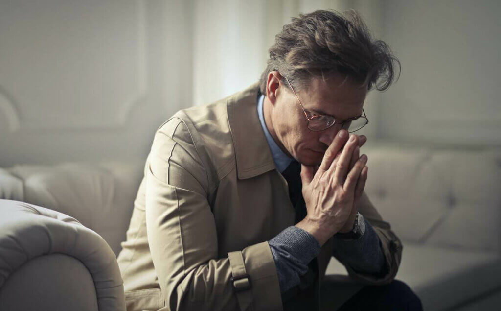 Un homme triste assis sur un canapé.