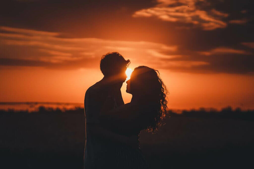 Couple enlacé face au coucher du soleil.