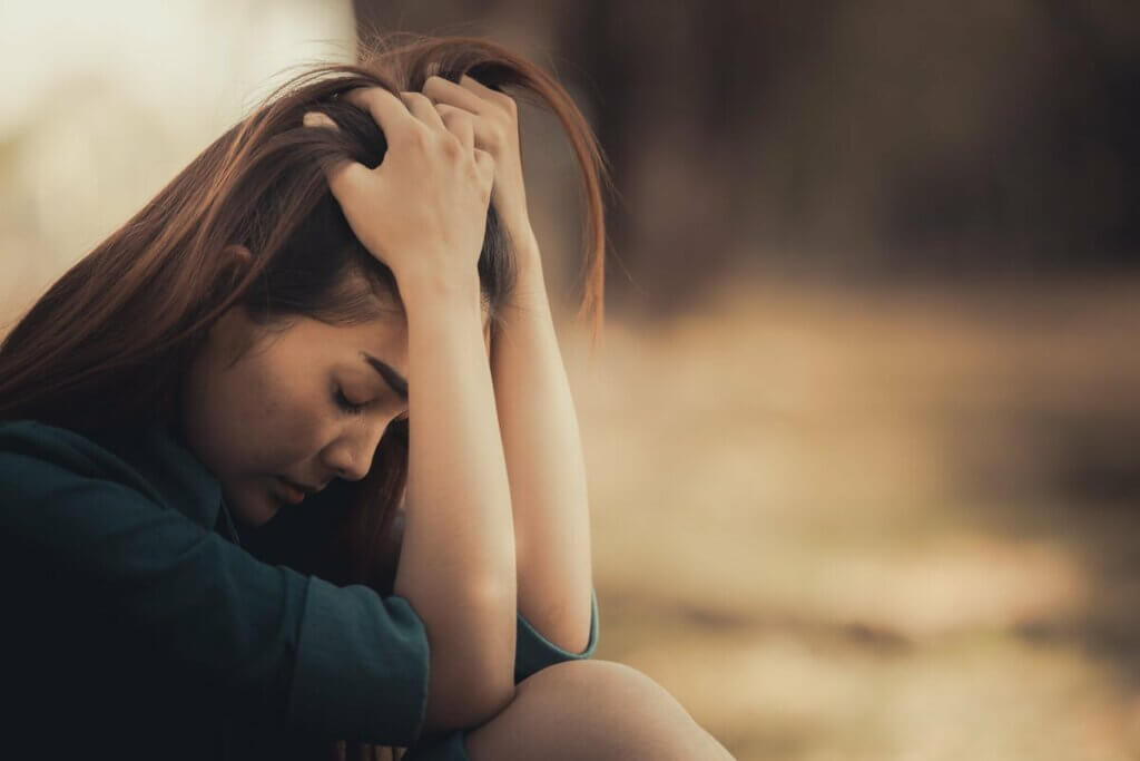 Une femme assise, l'air triste.