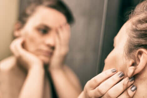 Une femme triste qui se regarde dans le miroir. 