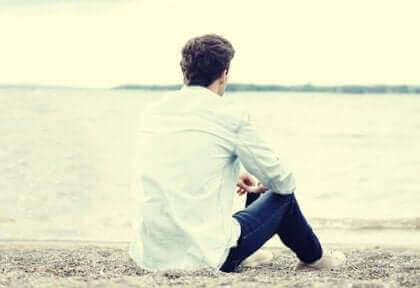 Un homme seul assis sur le sable.